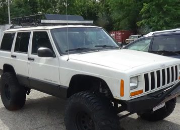 A white jeep with a large tire on the side.