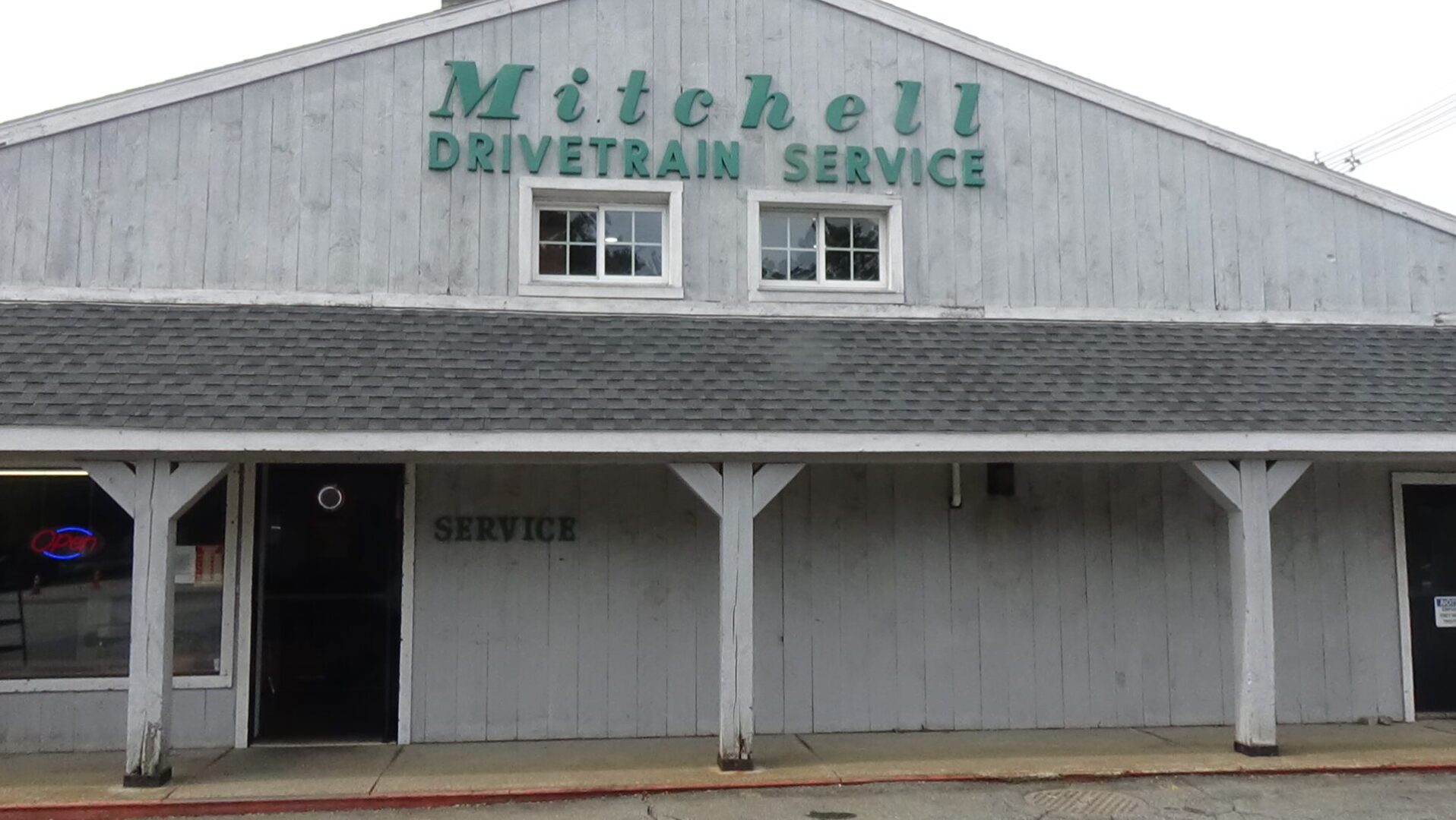 A white building with the name mitchell drivetrain service on it.